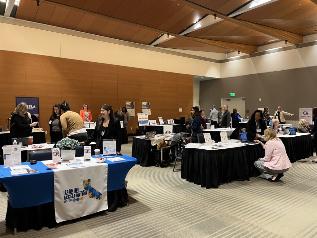 A photo of a ballroom with many smaller exhibitor tables. Each table representing an initiative within the California Statewide System of Support